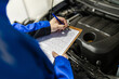 © zphoto83 - Mechanics perform maintenance check on vehicle engine while taking notes on clipboard