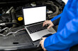 © zphoto83 - Technician using a blank screen laptop to diagnose issues under the hood of a car in an auto repair shop