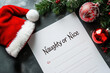© Klay - naughty or nice list with santa hat and christmas decorations on a dark background, holiday planning concept