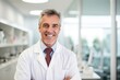 © Regina - A middle age man seasoned dentist in a white coat in a modern dental office, looking into the camera with a reassuring smile, highlighting his expertise and professionalism.