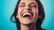 © BarboraWurflova - Laughter radiates through a beaming smile against a vibrant blue backdrop, capturing an authentic moment of joy and carefree spirit.