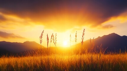 Wall Mural - Silhouetted grass sways gently in a vibrant sunset landscape, with golden skies and mountains in the background, Ideal for nature-themed projects, tranquil settings, or inspirational content,