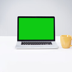 Wall Mural - laptop, green screen and coffee on desk for space, mockup and online on white studio background. bla