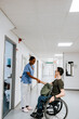 © Maskot - Smiling female healthcare worker doing handshake with boy sitting on wheelchair at hospital