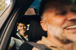 © Maskot - Portrait of smiling young man sitting in back seat of car