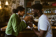 © Maskot - Multiracial couple toasting drinks while celebrating at bar