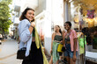 © Maskot - Smiling woman trying dress while shopping with friends at street market