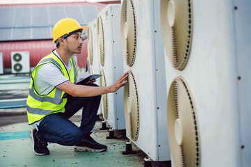 man in a yellow vest is checking an air conditioner