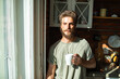 © Marko Geber - Portrait of a young man enjoying morning coffee by the window in cozy kitchen