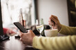 © VaCity - Woman browsing internet on mobile phone in coffee shop. Close up shot