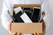 © vejaa - Man hands holding cardboard box with used smartphones. Donation, charity, e-waste, electronic gadgets for reuse, refurbish, recycling concept