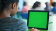 © DREAMERLYN STUDIO - A focused student taking notes while attending a virtual class, with a green screen iPad displayed in the foreground