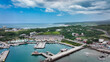 © Dave - Aerial view of a vibrant harbor in Taiwan with boats and lush green hills in the background