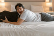 © Sevendeman - Happy Asian man lying on the hotel bed with luggage travel bag.