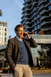 © BGStock72 - Businessman in smart attire walking while talking on phone in modern urban setting during sunny afternoon