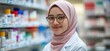 © Ashalina - Smiling pharmacist in hijab, in pharmacy.
