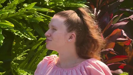 Wall Mural - Young woman against the background of tropical plants, breathing air and enjoying summer.