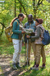 © AnnaStills - Vertical shot of African American family standing in autumn forest and discussing map