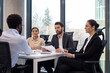© Liubomir - Job interview scene with diverse business team and candidate engaging professionally in modern office setting. Panel holding documents, tables equipped for corporate discussions.