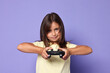 © New Africa - Cute little girl playing video game with controller on violet background