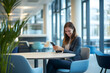 © Jannik - A smiling business woman using her phone while sitting at the table in a modern office