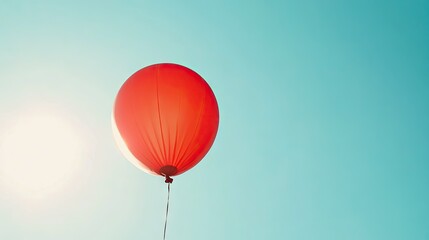 Bright Red Balloon Floating in Clear Blue Sky