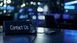 © Sam - A modern desk with a phone and 'Contact Us' sign, illuminated in cool blue tones, evoking a calm professional atmosphere.