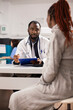 © DC Studio - African american woman receives pregnancy care advice from her obstetrician during medical checkup. Black male physician using clipboard to show pregnant lady details about her medications and health.