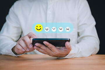 Fototapete - Person holding a smartphone select a happy face icon from a feedback scale with five emoji option, symbolizing customer satisfaction, review, and positive user experience in an online feedback system.