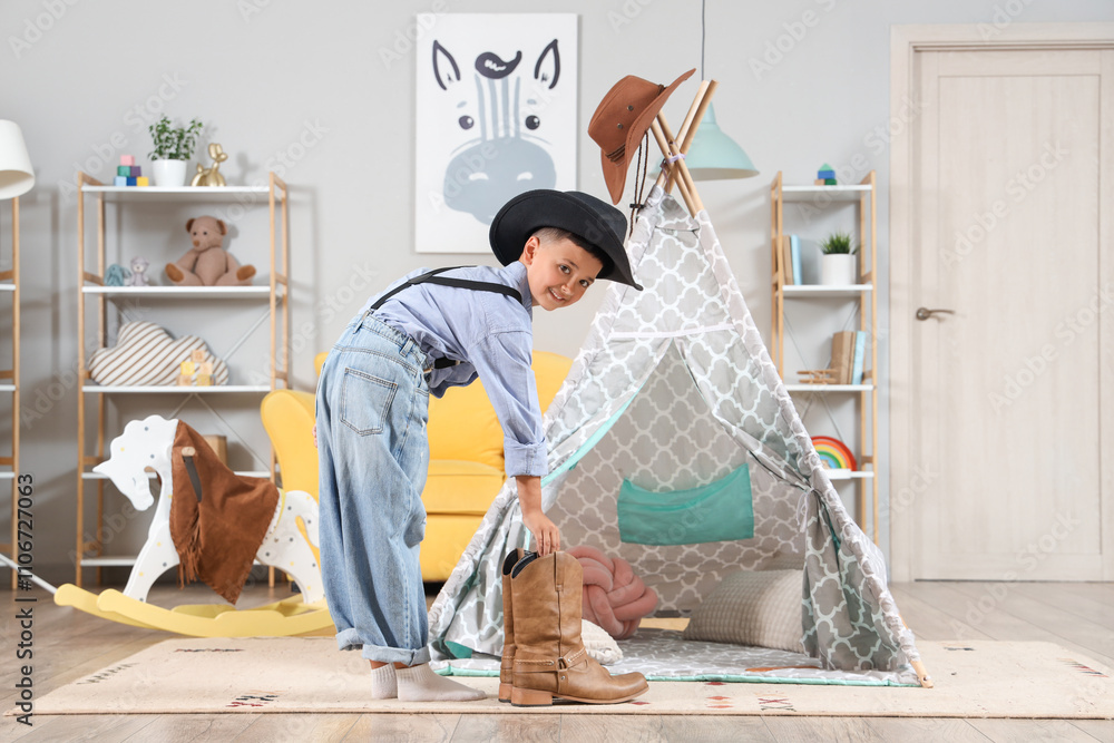 Cute little cowboy with boots at home