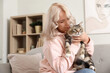 © Pixel-Shot - Beautiful mature woman with cute cat sitting on sofa at home