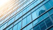 © lertsakwiman - A close-up view of a modern glass building reflecting sunlight, showcasing its sleek architectural design and blue-tinted windows.