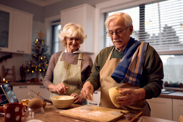 Wall Mural - Smiling senior man and his wife baking together for Christmas holidays.