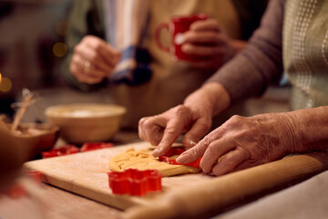 Wall Mural - Close up of senior woman using cookie cutter while baking for Christmas.