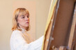 © puhimec - Young female artist painting on easel in studio. Art concept. A woman draws.