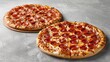 © Lasvu - Two pepperoni pizzas, small and large, seen from the side on a gray backdrop