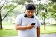 © Queenmoonlite Studio - Young Asian Fat Man in Sportswear Using Smartphone While Workout in The Park