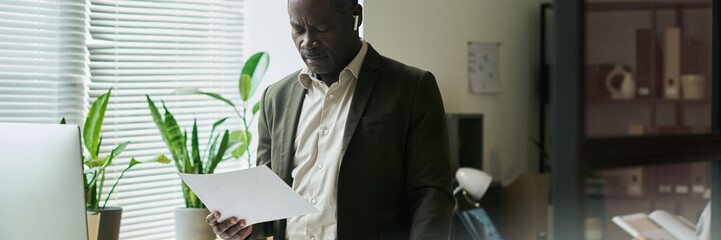Poster - Header of chief executive officer standing by workplace with desktop computer and looking through paper document