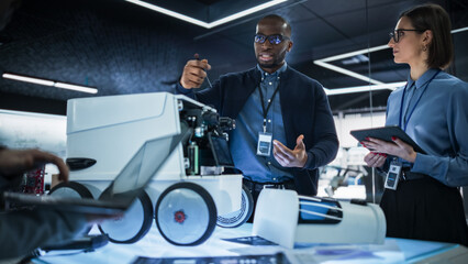 Fototapete - Team of Industrial Engineers Working on a Mobility Robot at a Startup Factory. Multiethnic Male and Female Scientists Discussing an Automated AI Robotic Delivery Machine in a Laboratory