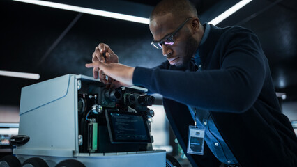 Fototapete - African Engineer Using a Screwdriver While Developing a Remotely Controlled Delivery Robot. Black Specialist Working in High Tech Research Laboratory with Modern Equipment