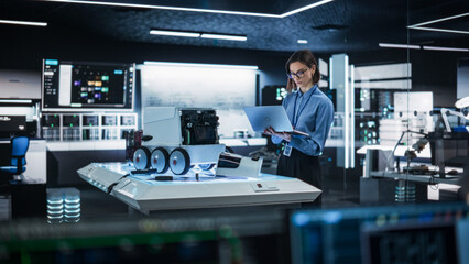 Fototapete - Portrait of a Female Engineer Using a Laptop While Developing a Remotely Controlled Delivery Robot.Technical Specialist Working in High Tech Research Laboratory with Modern Equipment