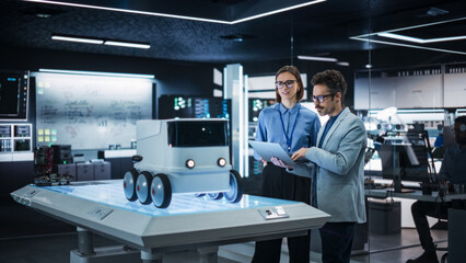 Fototapete - Portrait of Two Colleagues Working in a Research Facility, Using Laptop Computer to Develop a Futuristic Robot for Autonomous Deliveries. Manufacturing Specialist Doing a Demonstration to Team Manager