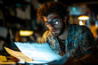 © DudeDesignStudio - A young man studies documents under warm light in a cozy, cluttered workspace.