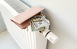 © Pawel - Dollar bills and a wallet lie on the radiator. The concept of rising costs for heating apartments.