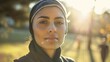 © iuricazac - A woman with a headscarf likely a hijab in a serene Outdoor setting possibly a park or garden with the Sun shining brightly behind her.