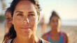 © iuricazac - A close-up portrait Of a middle-aged woman with dark hair set against a blurred beach background with Other women in the distance.