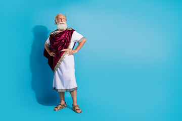 Full length photo of attractive old man look empty space confident pose dressed greek god emperor actor costume isolated on blue background