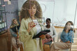 © DragonImages - Businesswoman presenting strategy plan on glass board, engaging with team members during collaborative office meeting. Team focused on project presentation and discussion