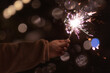© Leka - holiday and party concept, sparklers in hands on a dark background