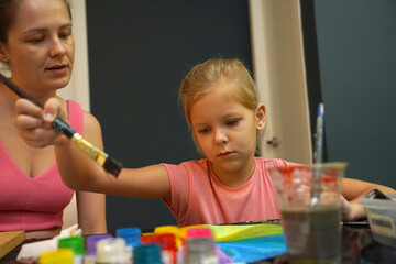 Wall Mural -  A mother and her young daughter engage in a colorful painting activity 